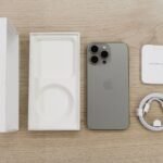 buy original iPhone accessories from Amazon in Pakistan – Flat lay view of the newest Apple iPhone model, box, and charging accessories on a wooden table.