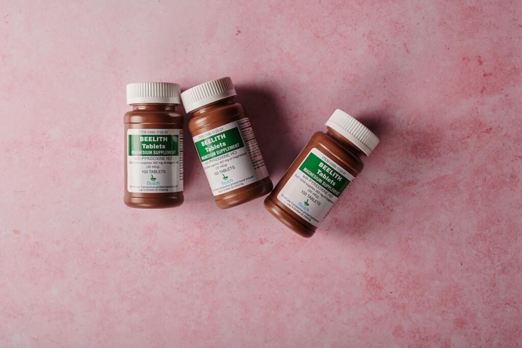 fake health supplements Pakistan – Three brown bottles of magnesium tablets on a soft pink background, ideal for health-themed content.