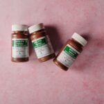fake health supplements Pakistan – Three brown bottles of magnesium tablets on a soft pink background, ideal for health-themed content.