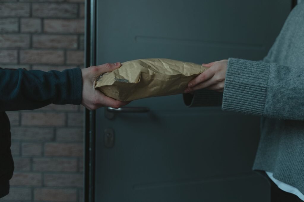 artificial hymen kit in pakistan – Close-up of hands exchanging a package at a doorway, symbolizing home delivery service.