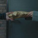 artificial hymen kit in pakistan – Close-up of hands exchanging a package at a doorway, symbolizing home delivery service.