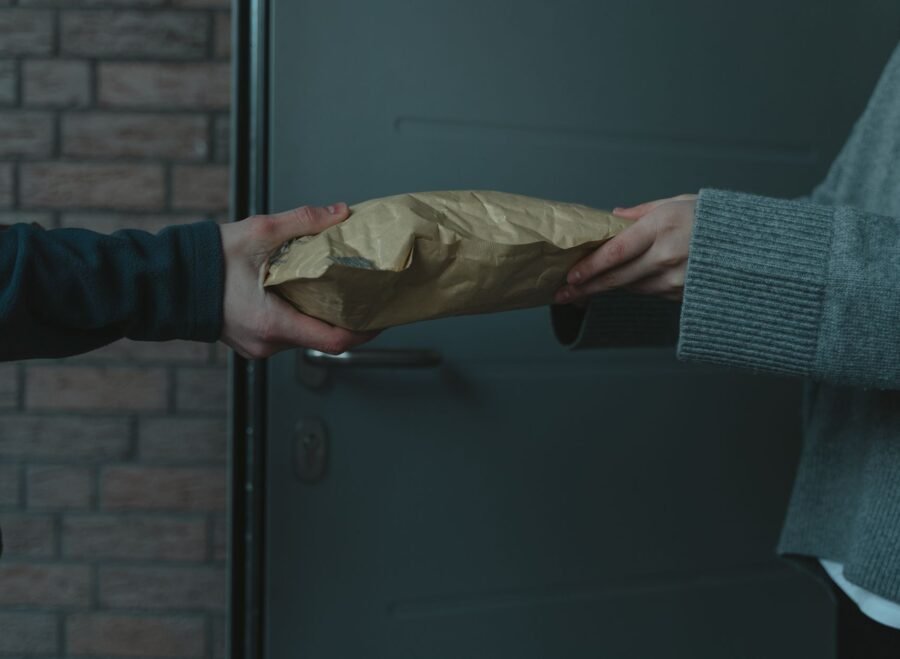 artificial hymen kit in pakistan – Close-up of hands exchanging a package at a doorway, symbolizing home delivery service.