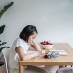 baby study table chair set price in pakistan – Asian child reading and writing at home, surrounded by plants and books, creating a learning environment.