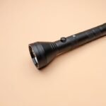 search light price in pakistan – A sleek black flashlight lying on a beige surface, perfectly framed for design projects.