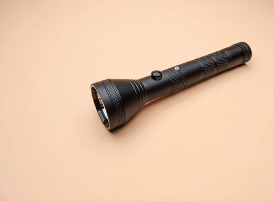 search light price in pakistan – A sleek black flashlight lying on a beige surface, perfectly framed for design projects.