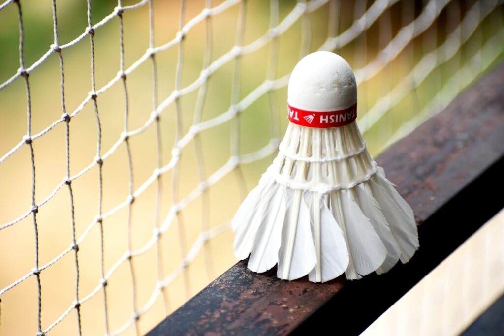 badminton net price in pakistan – A detailed view of a shuttlecock resting on a badminton net outdoors.