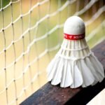 badminton net price in pakistan – A detailed view of a shuttlecock resting on a badminton net outdoors.