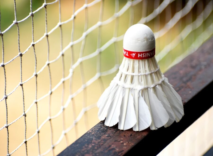 badminton net price in pakistan – A detailed view of a shuttlecock resting on a badminton net outdoors.