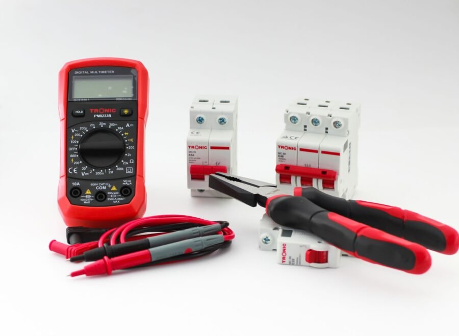 digital ampere meter – Close-up of a digital multimeter with electrical tools and circuit breakers on a white background.