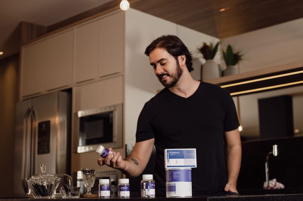 GNC Mega Men price in Pakistan – Man in a modern kitchen holding a vitamin supplement bottle, surrounded by health products.