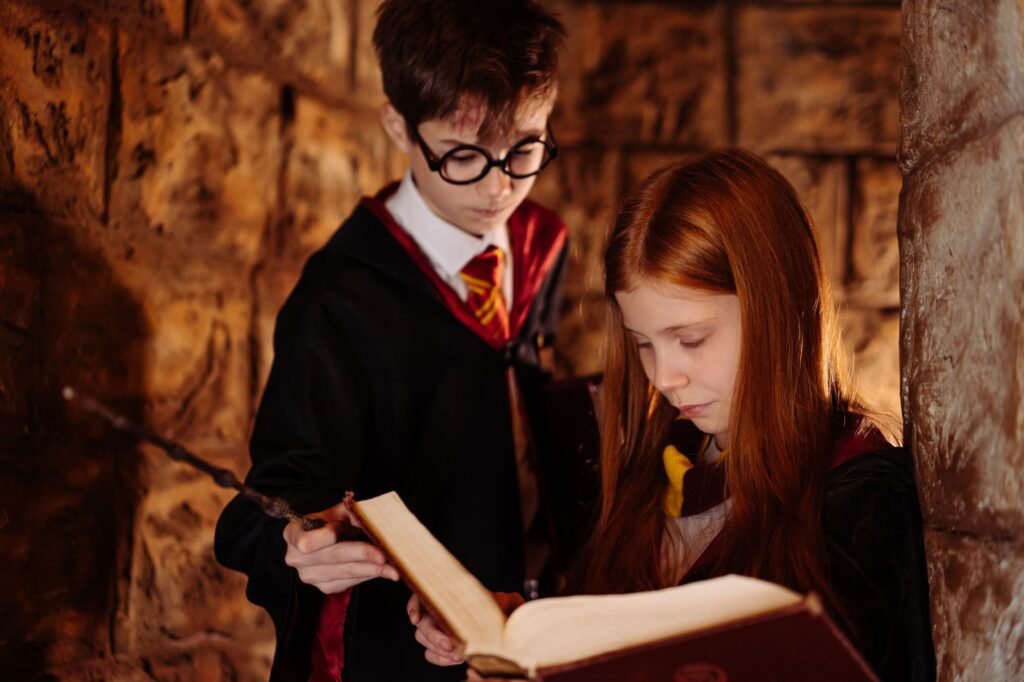 harry potter costume pakistan – Two children in wizard costumes reading a spellbook in a dimly lit stone room.