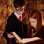 harry potter costume pakistan – Two children in wizard costumes reading a spellbook in a dimly lit stone room.