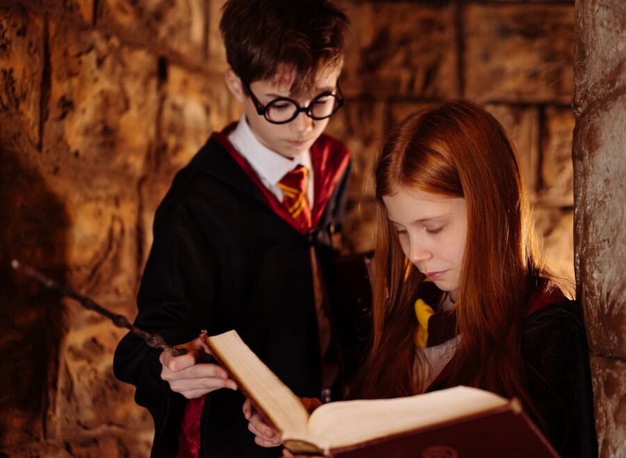 harry potter costume pakistan – Two children in wizard costumes reading a spellbook in a dimly lit stone room.