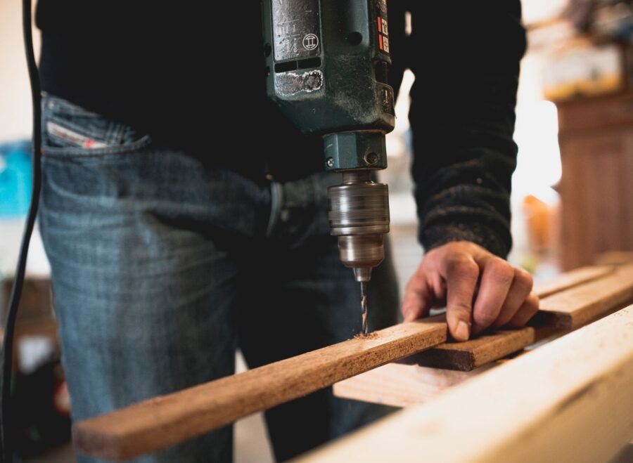 makita drill machine price in pakistan – Close-up of a person using an electric drill on a wooden plank, showcasing detailed woodworking skills.