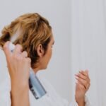 procomil delay spray in pakistan – A woman uses hair spray for styling in a bright indoor setting.