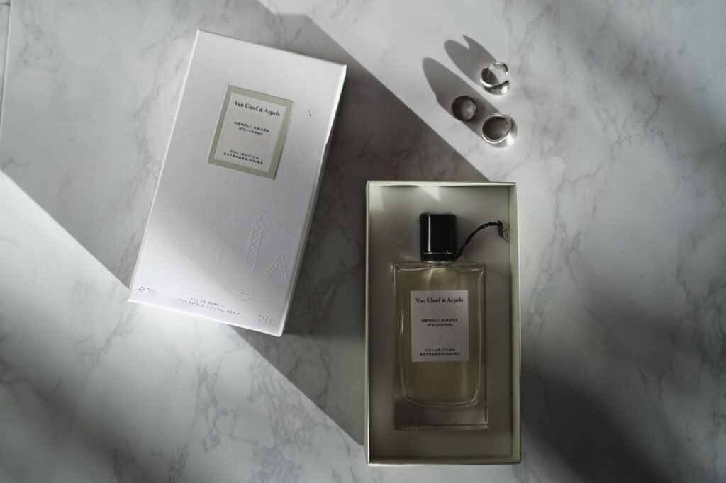 woody intense perfume price in pakistan – A top view of a luxury perfume bottle and box on a marble surface.