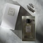 woody intense perfume price in pakistan – A top view of a luxury perfume bottle and box on a marble surface.