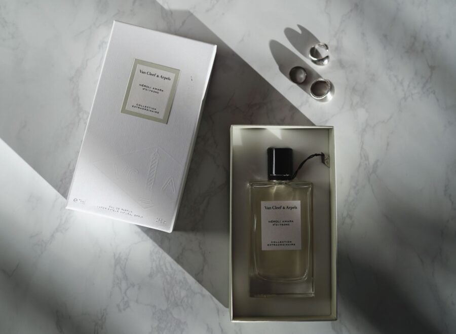 woody intense perfume price in pakistan – A top view of a luxury perfume bottle and box on a marble surface.