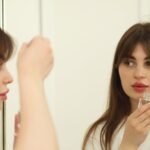 acnes c10 serum price in pakistan – A young woman applying skincare serum in front of a mirror indoors. Perfect for beauty and self-care themes.