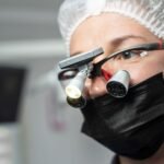 dental loupes price in pakistan – Female dentist wearing dental loupes and face mask, focused on patient care.