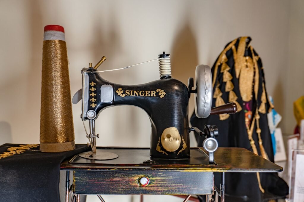 embroidery frame price in pakistan – Classic Singer sewing machine with gold embroidery thread and ornate fabric, highlighting traditional craftsmanship.