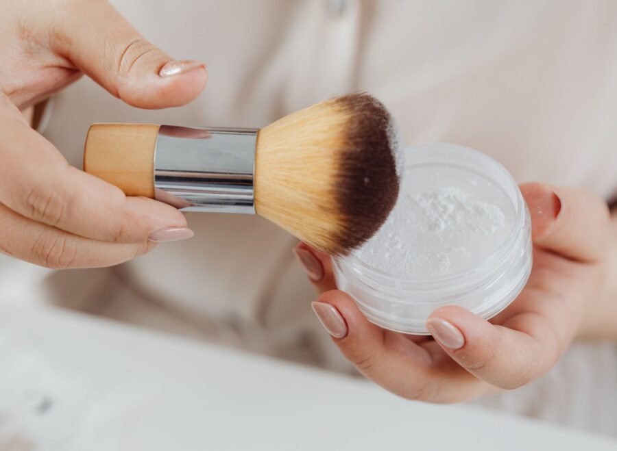Etude face powder price in Pakistan – Close-up view of a hand applying face powder with a makeup brush, perfect for beauty and lifestyle concepts.