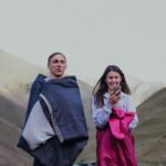 sleeping bag pakistan – A man and woman wrapped in sleeping bags enjoying nature and outdoor camping in mountainous terrain.